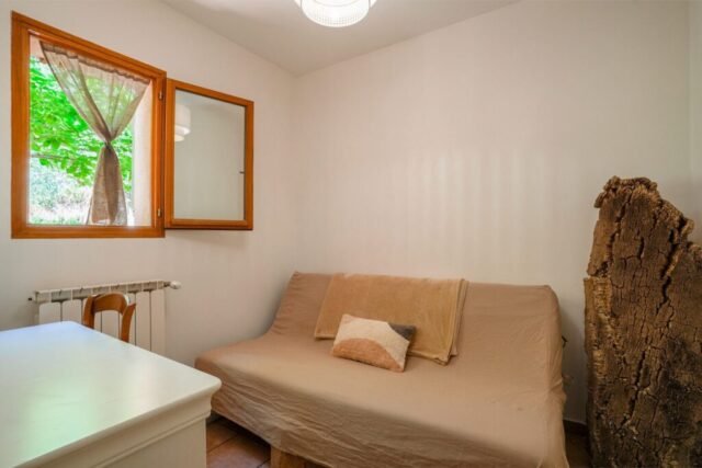 Petite chambre lumineuse avec banquette-lit et rideaux en lin devant la fenêtre Petite chambre lumineuse avec banquette-lit et rideaux en lin devant la fenêtre