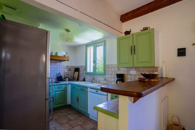 Cuisine équipée aux façades vert amande avec bar en bois et lave-vaisselle Cuisine équipée aux façades vert amande avec bar en bois et lave-vaisselle