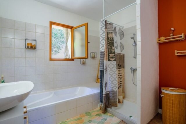 Salle de bains avec baignoire, douche et fenêtre ouverte sur les arbres Salle de bains avec baignoire, douche et fenêtre ouverte sur les arbres